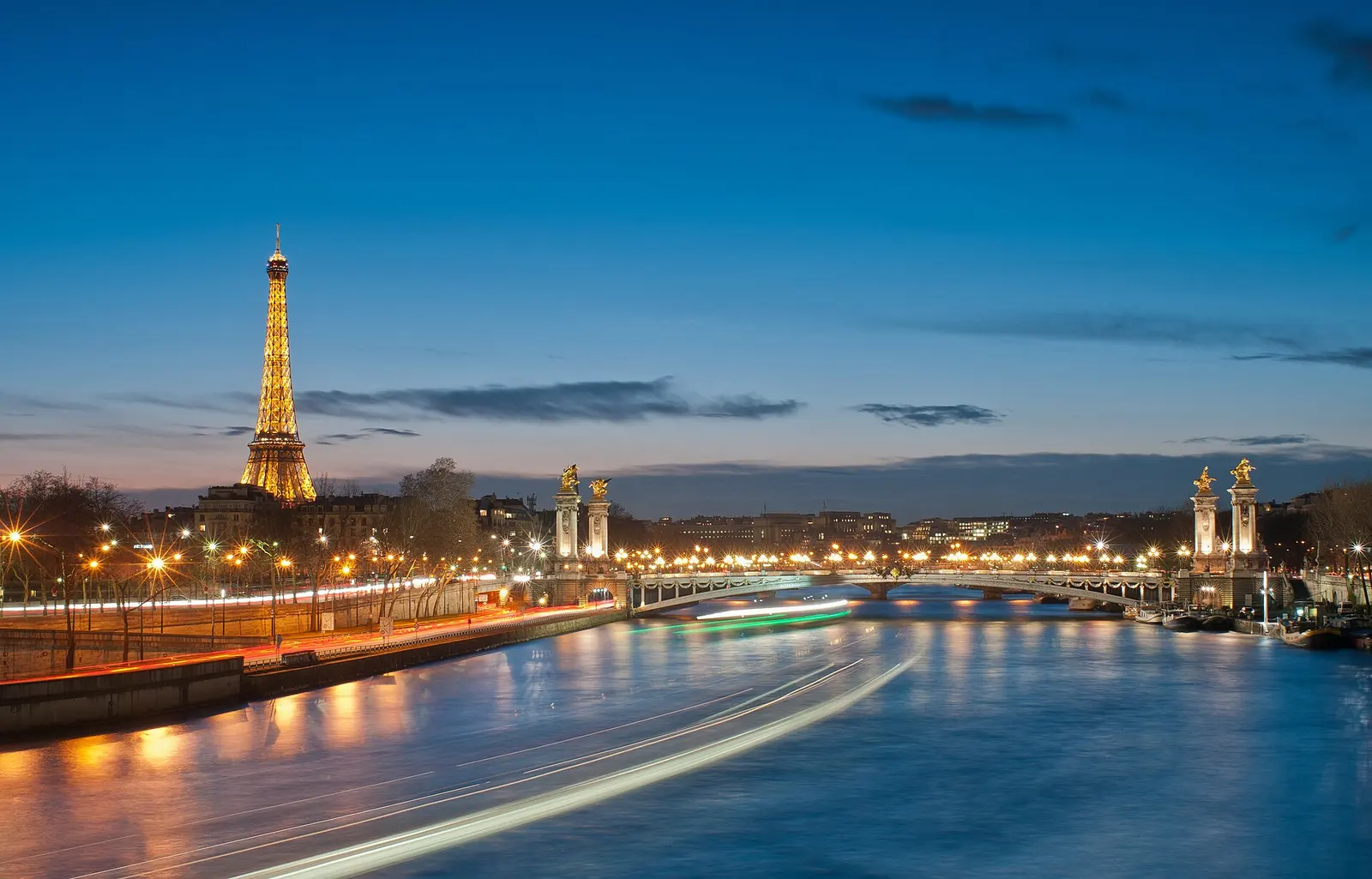 The Eiffel Tower lit up at night above the Seine